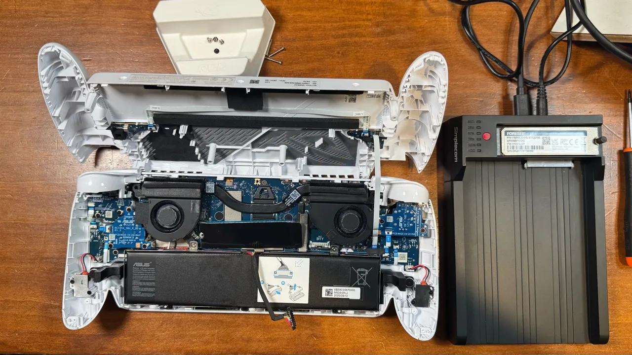 The opened handheld computer beside its removed NVMe drive connected to an external adapter.